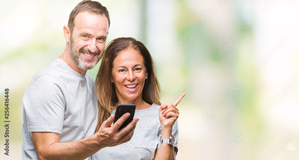 Middle age hispanic couple texting message on smartphone ver isolated background very happy pointing with hand and finger to the side Middle age hispanic couple texting message on smartphone ver isolated background very happy pointing with hand and finger to the side