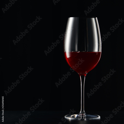 Wine glass with red wine on dark surface isolated on black