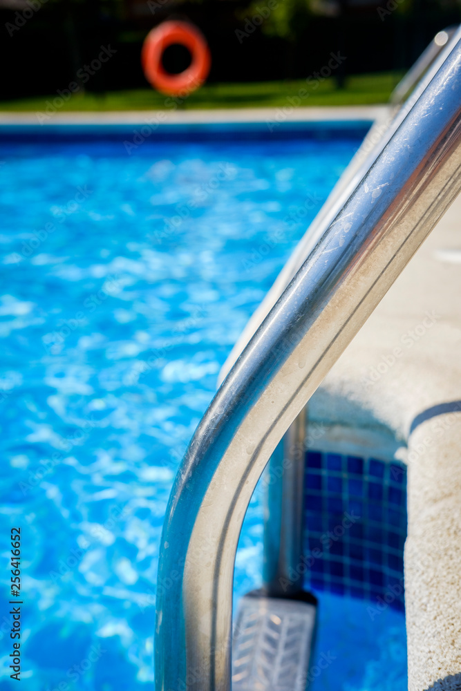 Obraz premium Staircase on the swimming pool edge with blue water copy space during a sunny summer day
