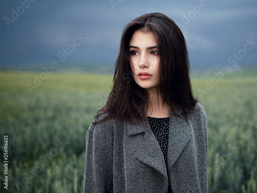 Portrait beautiful youth brunette model with green eyes, perfect skincare, dressed casual, posing outside, on a amazing landscape background.