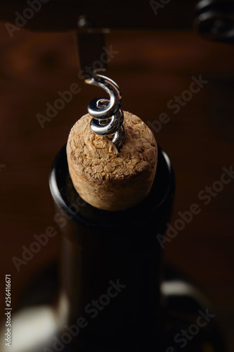 Wine bottle with wooden cork and corkscrew on brown