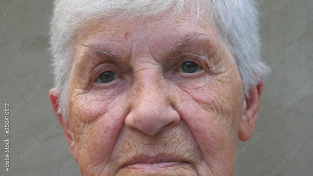 Portrait of old grandmother with a sad sight. Wrinkled face of elderly lady looking into camera. Sorrow facial expression of granny. Close up gaze of mature woman Portrait of old grandmother with a sad sight. Wrinkled face of elderly lady looking into camera. Sorrow facial expression of granny. Close up gaze of mature woman