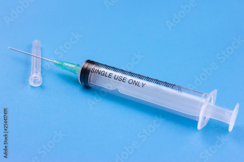 Disposable syringe and its packaging on a blue background