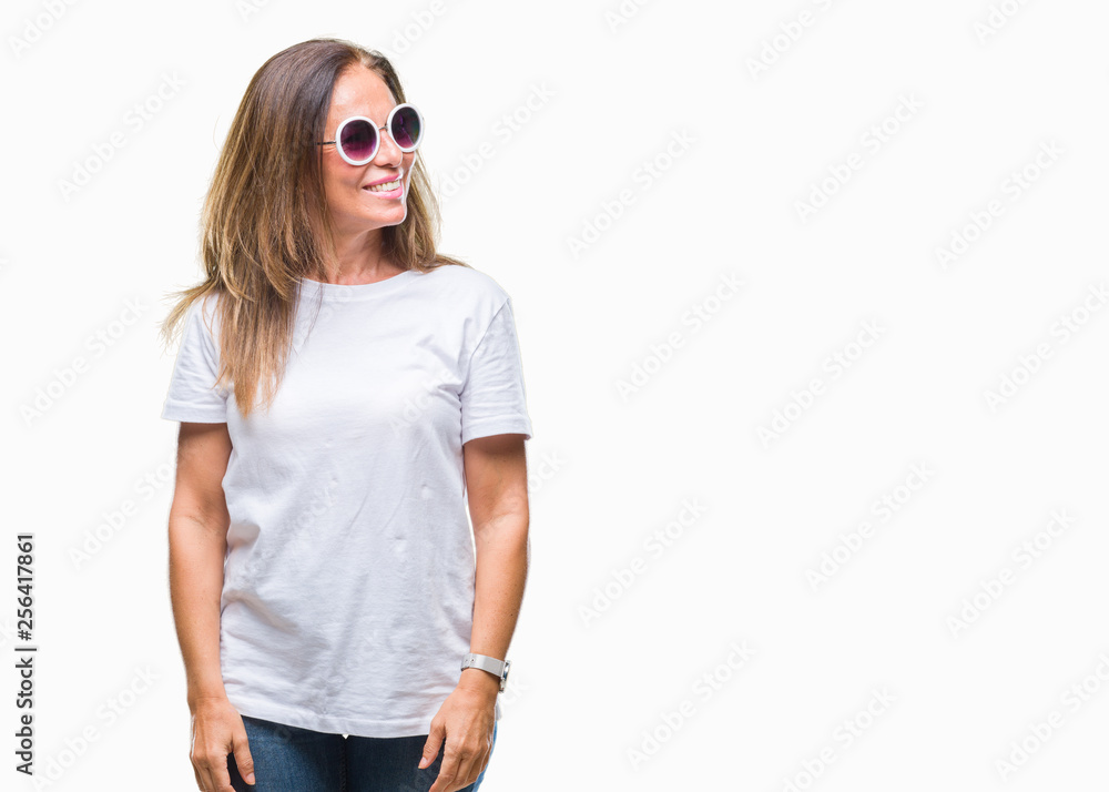 Middle age hispanic woman wearing fashion sunglasses over isolated background looking away to side with smile on face, natural expression. Laughing confident. Middle age hispanic woman wearing fashion sunglasses over isolated background looking away to side with smile on face, natural expression. Laughing confident.