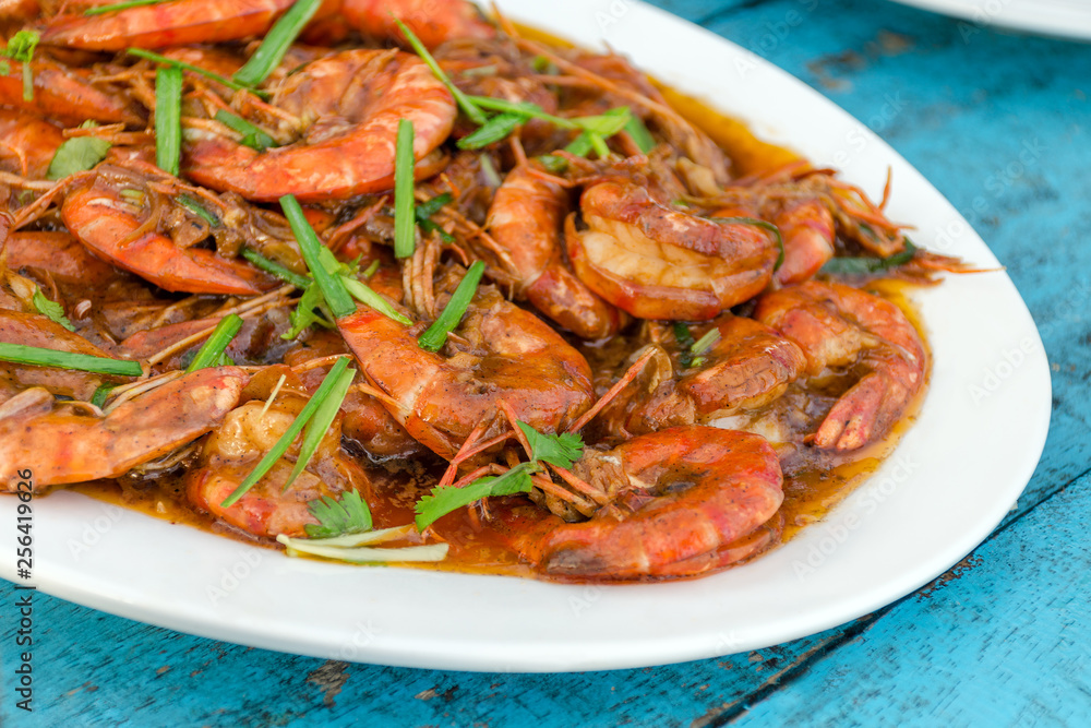 Shrimp in a sauce with herbs on wooden table - a traditional Sri Lankan dish.