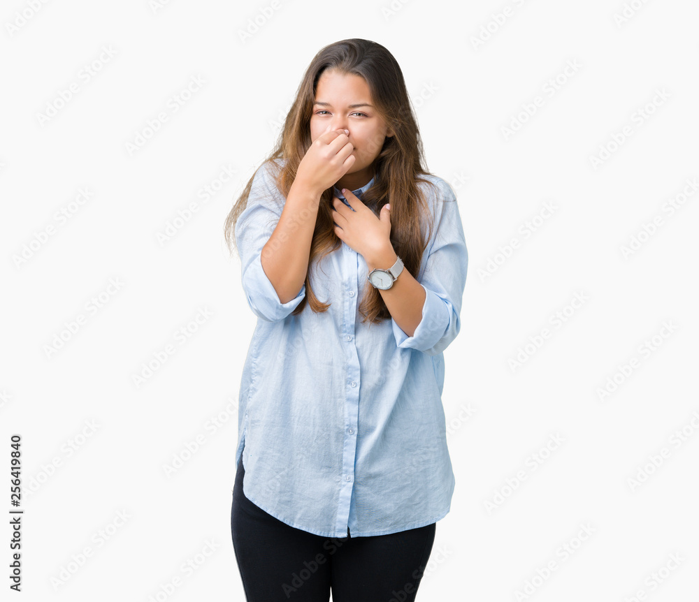 Young beautiful brunette business woman over isolated background smelling something stinky and disgusting, intolerable smell, holding breath with fingers on nose. Bad smells concept. Young beautiful brunette business woman over isolated background smelling something stinky and disgusting, intolerable smell, holding breath with fingers on nose. Bad smells concept.