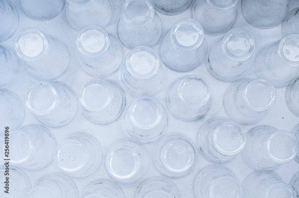 Empty plastic glasses on a white background, top view. Abstract backdrop of plastic utensils. Empty plastic glasses on a white background, top view. Abstract backdrop of plastic utensils.