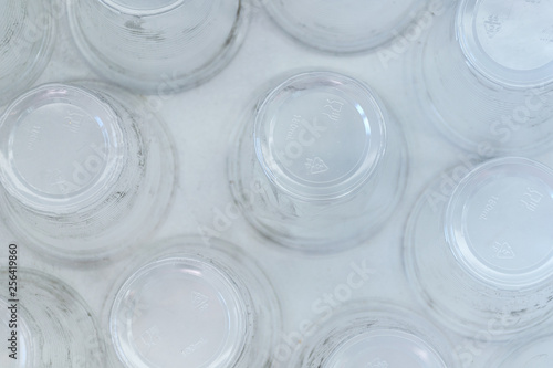 Dirty empty plastic glasses on a white background, top view, close up. Abstract backdrop of plastic utensils.
