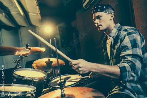 selective focus of handsome drummer holding drum sticks while playing drums photo
