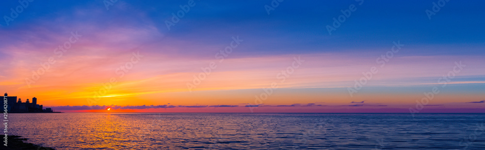Naklejka premium Sunset over Malecon and Atlantic Ocean with residential building in background - Havana, Cuba 