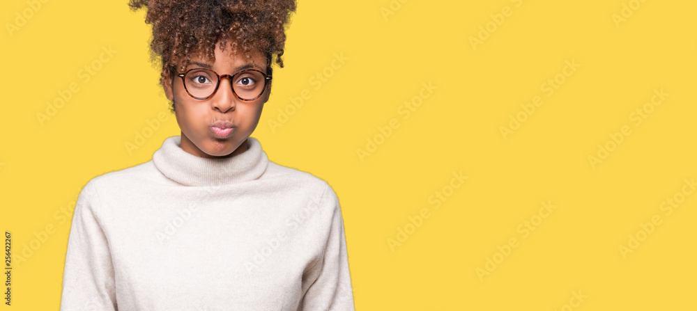 Beautiful young african american woman wearing glasses over isolated background puffing cheeks with funny face. Mouth inflated with air, crazy expression. Beautiful young african american woman wearing glasses over isolated background puffing cheeks with funny face. Mouth inflated with air, crazy expression.