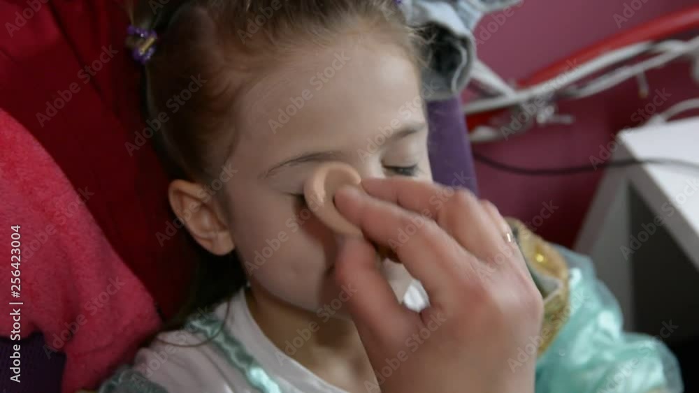 Do makeup to child. The mother paints the face of a little girl. Do makeup to child. The mother paints the face of a little girl.