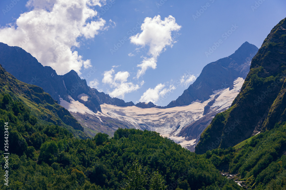 A large glacier between the mountains on a summer, clear day. High in the Caucasian mountains, around dombai.