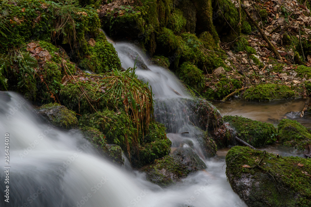 Wasserfall mit Steinen voller Moos Wasserfall mit Steinen voller Moos
