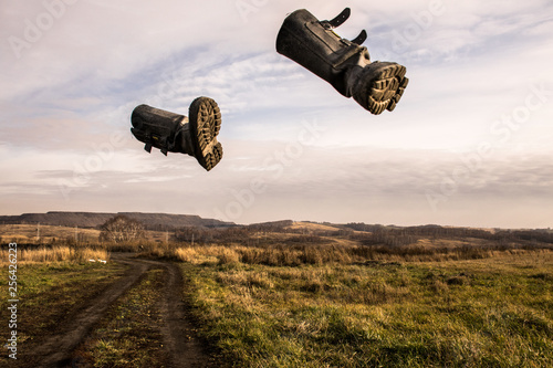 Two black boots fly across the sky in the middle of an autumn field