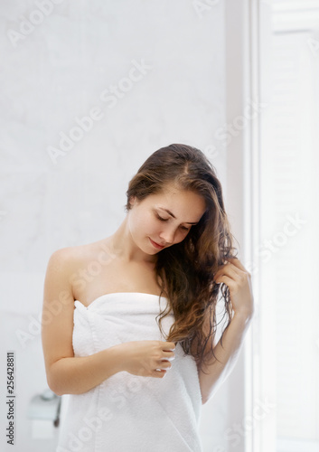 Portrait Of Beautiful Young Female Model  in  Bath Applying Hair Oil. Closeup Of Sexy Woman In Towel Drying Wet Long Hair. Health And Beauty Concept. Protection moisturizing.