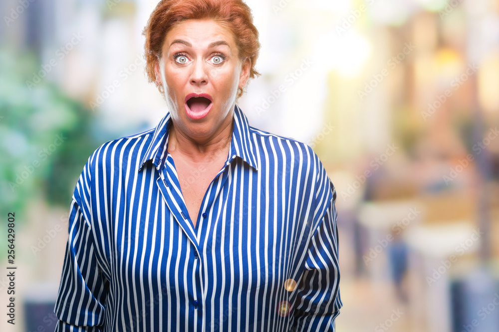 Atrractive senior caucasian redhead woman over isolated background afraid and shocked with surprise expression, fear and excited face. Atrractive senior caucasian redhead woman over isolated background afraid and shocked with surprise expression, fear and excited face.