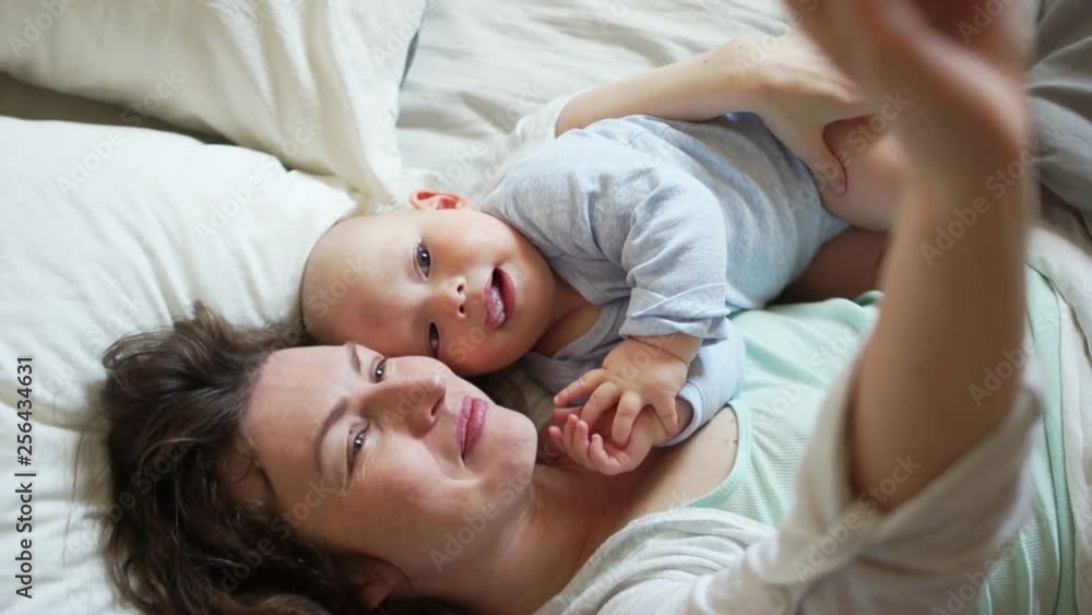 Self mom and baby in bed in the early morning. Concept of happy motherhood, mother's day Self mom and baby in bed in the early morning. Concept of happy motherhood, mother's day