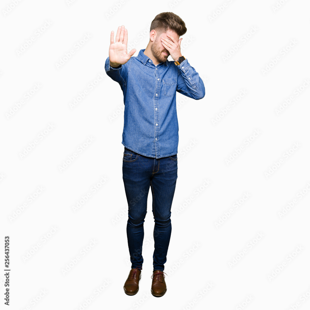 Fototapeta premium Young handsome blond man wearing casual denim shirt covering eyes with hands and doing stop gesture with sad and fear expression. Embarrassed and negative concept.
