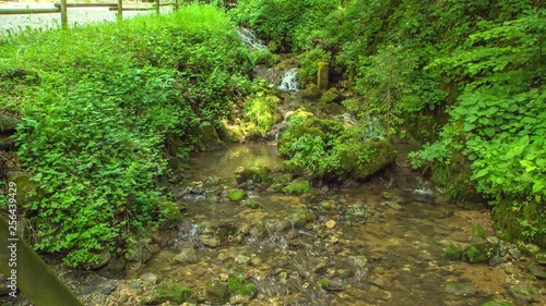 Stream under a bridge on a nice summer day. There is an entrance to the cave. photo