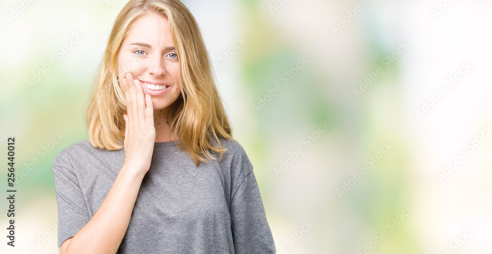 Beautiful young woman wearing oversize casual t-shirt over isolated background touching mouth with hand with painful expression because of toothache or dental illness on teeth. Dentist concept.