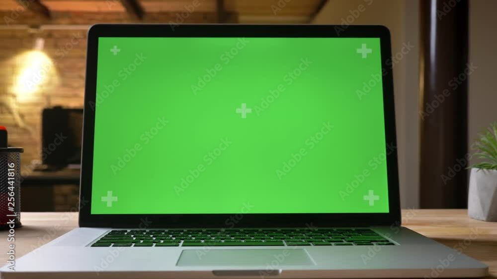 Closeup shoot by camera moxing from bottom up of the laptop with green screen on the table indoors in the office Closeup shoot by camera moxing from bottom up of the laptop with green screen on the table indoors in the office