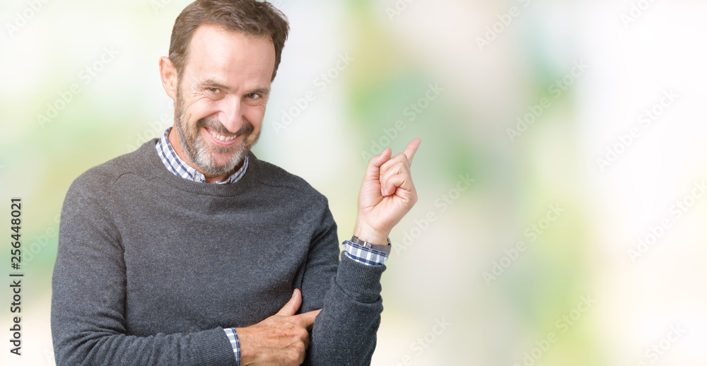 Handsome middle age senior man wearing a sweater over isolated background with a big smile on face, pointing with hand and finger to the side looking at the camera. Handsome middle age senior man wearing a sweater over isolated background with a big smile on face, pointing with hand and finger to the side looking at the camera.