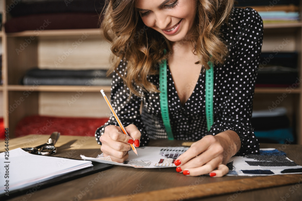 Fototapeta premium Smiling young woman seamstress working