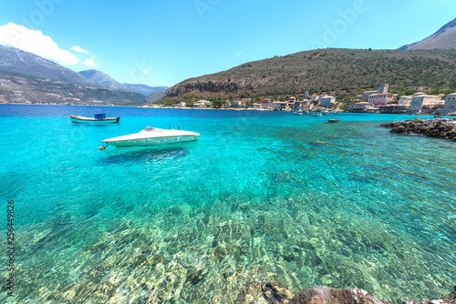 Speedboat on turqoise water of meditteranean bay. Landscape image of Greek sea village.