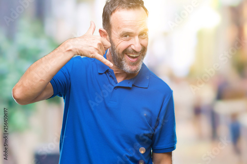 Middle age hoary senior man over isolated background smiling doing phone gesture with hand and fingers like talking on the telephone. Communicating concepts.