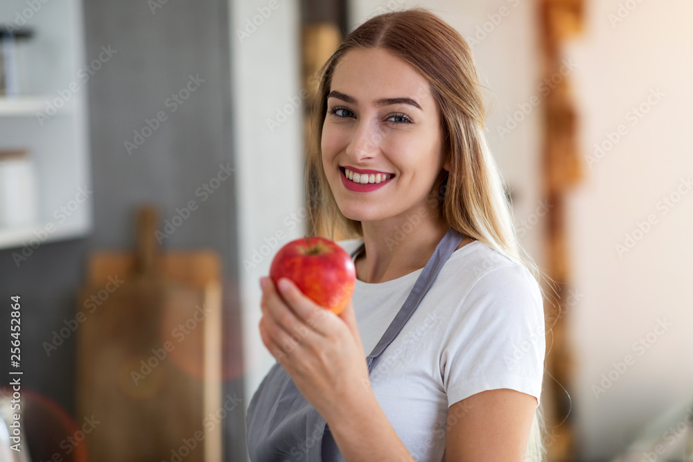 Young woman holding an apple and smiling Young woman holding an apple and smiling