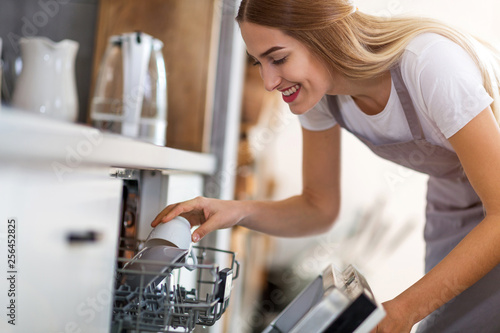 Woman putting dishes into dishwasher photo