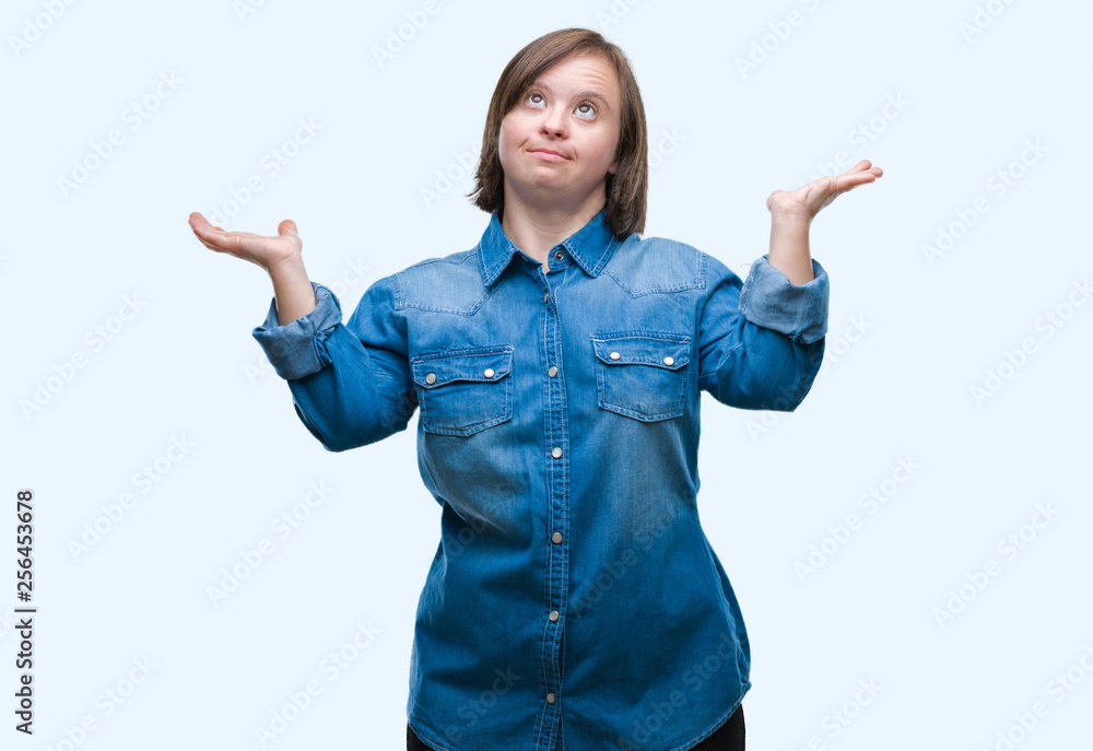 Young adult woman with down syndrome over isolated background clueless and confused expression with arms and hands raised. Doubt concept. Young adult woman with down syndrome over isolated background clueless and confused expression with arms and hands raised. Doubt concept.