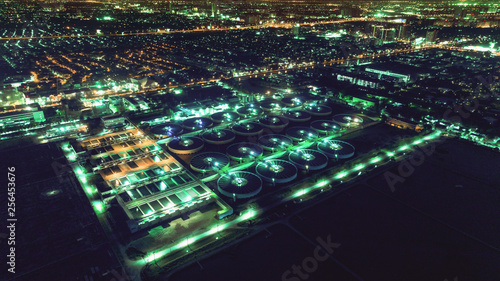 Aerial view water treatment plant at night with cityscape for environment concept.