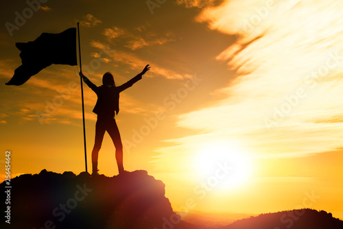 girl with a flag on top of the mountain against the evening sky. the achievement of the objectives, tourism, travel.