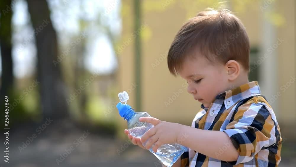 handsome boy drinks clear water from a bottle on a sunny day outside handsome boy drinks clear water from a bottle on a sunny day outside