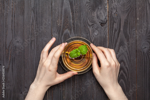 transparent cup of amber-colored black tea in female hands