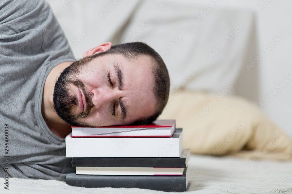 Young man is sleeping on his books. White background