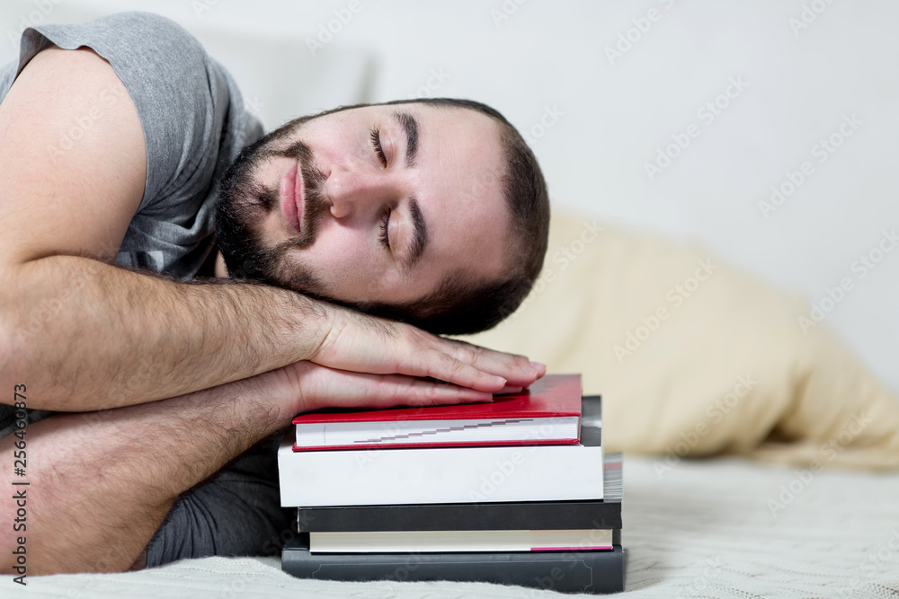 Obraz premium Young man is sleeping on his books. White background