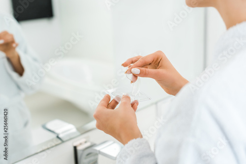 selective focus of woman holding eye patches in bathroom