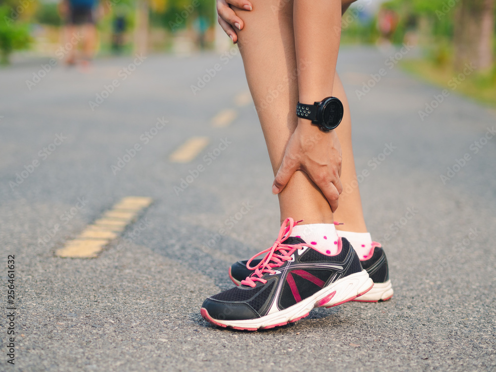 Athlete woman has ankle injury, sprained leg during running training. sport concept.