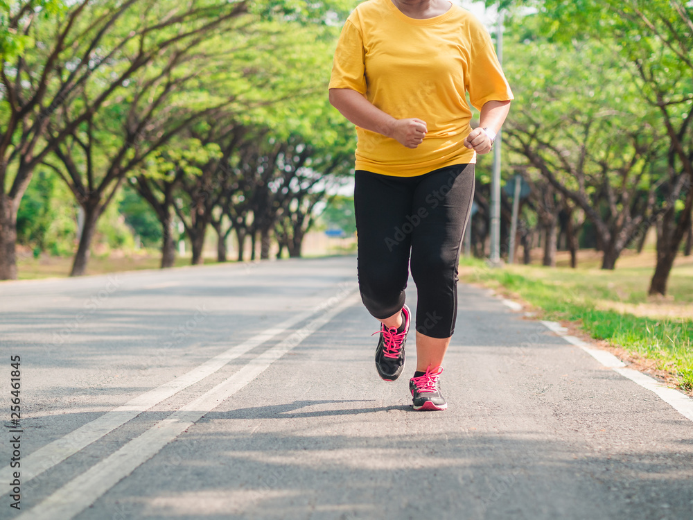 Overweight woman running in the park. Weight loss concept Overweight woman running in the park. Weight loss concept