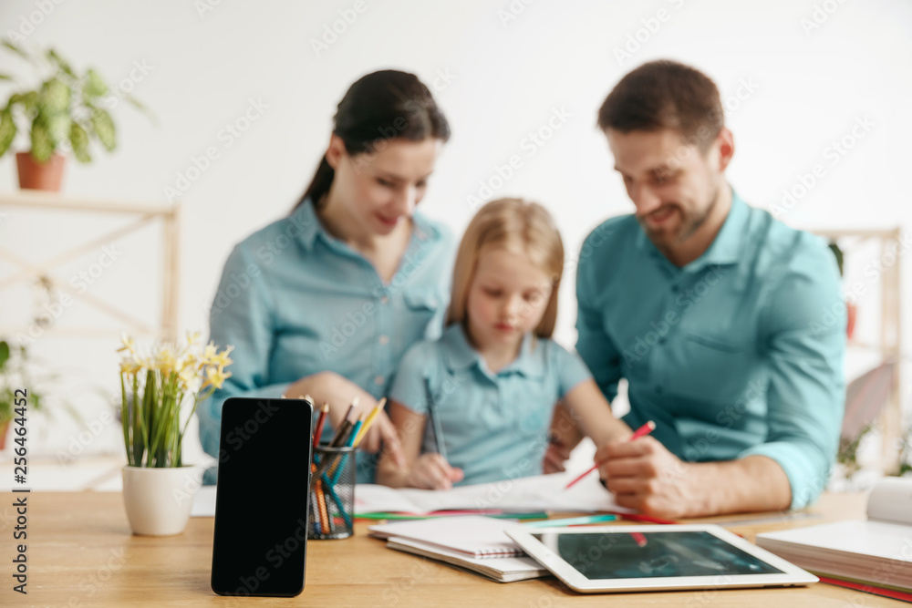 Father, mother and their daughter are smiling while spending time together. A day with family. Smartphone on the front is the mock up for your advertisement. Education, studying and knowledge sharing Father, mother and their daughter are smiling while spending time together. A day with family. Smartphone on the front is the mock up for your advertisement. Education, studying and knowledge sharing