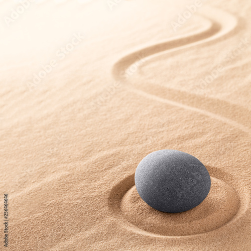 Spa wellness for inner life therapy and spiritual health. Zen meditation stone for relaxation. Concept for purity balance and harmony. Background with raked sand.