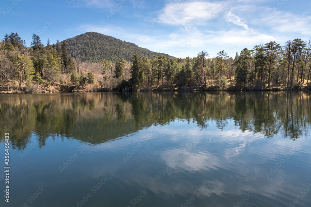 Paisaje de montañas, arboles y agua con reflejos en la sierra de Segovia, un día soleado