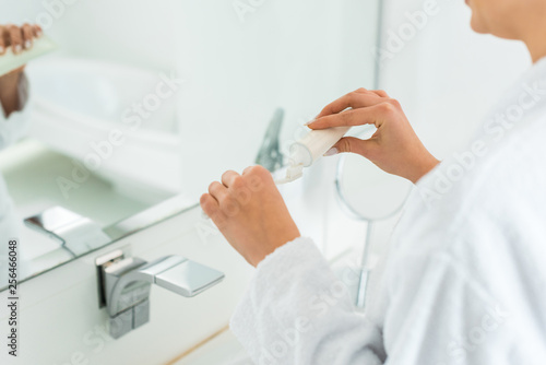 selective focus of woman applying toothpaste on toothbrush in bathroom © LIGHTFIELD STUDIOS