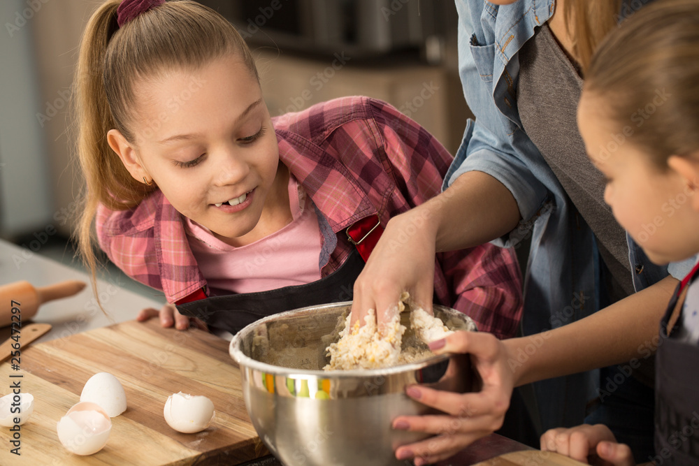 Happy mother cooking with her daughters at the kitchen Happy mother cooking with her daughters at the kitchen