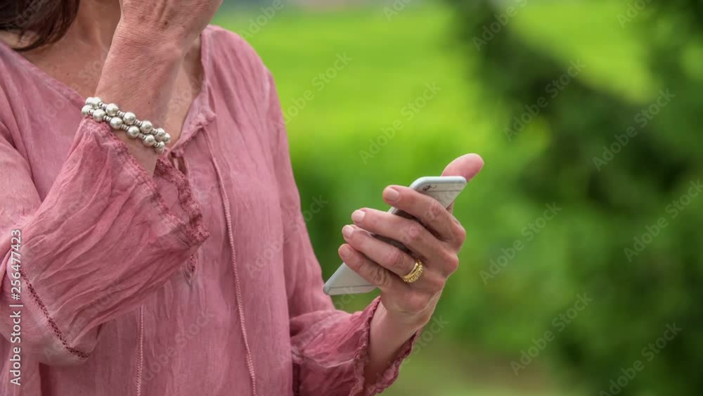 A middle-aged woman is using a touch screen phone. She is typing a text message. A middle-aged woman is using a touch screen phone. She is typing a text message.