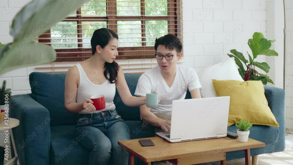 Two of young Asian couple family relaxing at sofa working on laptop for business finance, Asian lifestyle at home concept Two of young Asian couple family relaxing at sofa working on laptop for business finance, Asian lifestyle at home concept