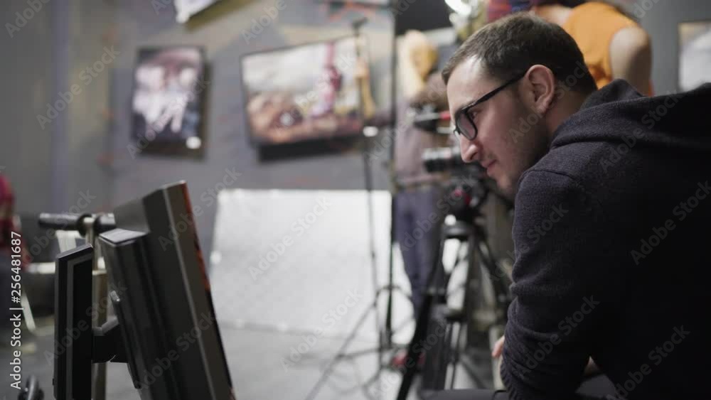 Male director with glasses is watching the monitor while directing a movie shooting Male director with glasses is watching the monitor while directing a movie shooting